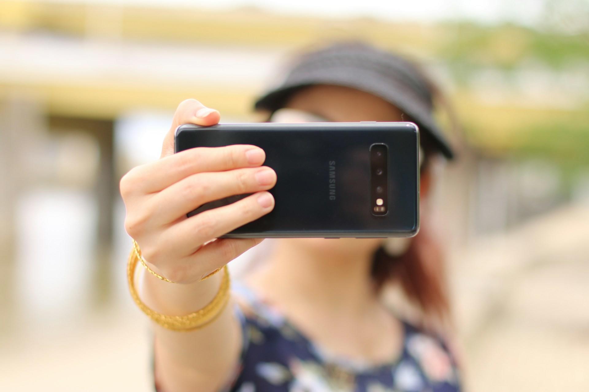Dame holder mobilen foran seg og tar en selfie.