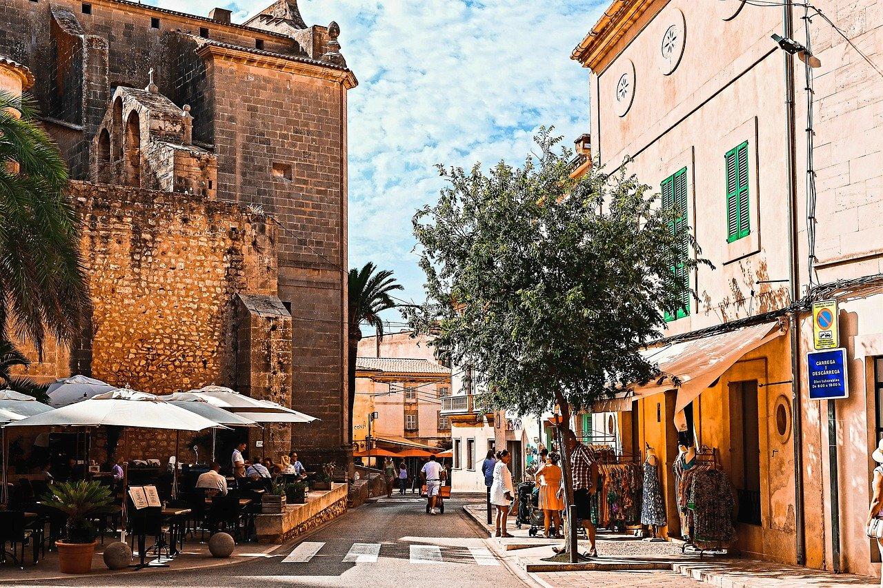 En sjarmerende gate i en spansk landsby med historiske bygninger og en utendørs kafé.