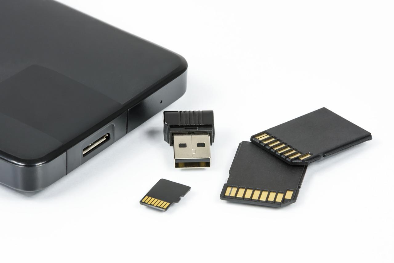 Et USB-minne, et SD-kort og et microSD-kort ved siden av en lukket bærbar datamaskin.