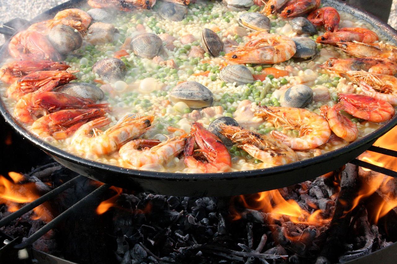 Tradisjonell spansk paella tilberedt over åpen flamme, fylt med sjømat, grønnsaker og ris.