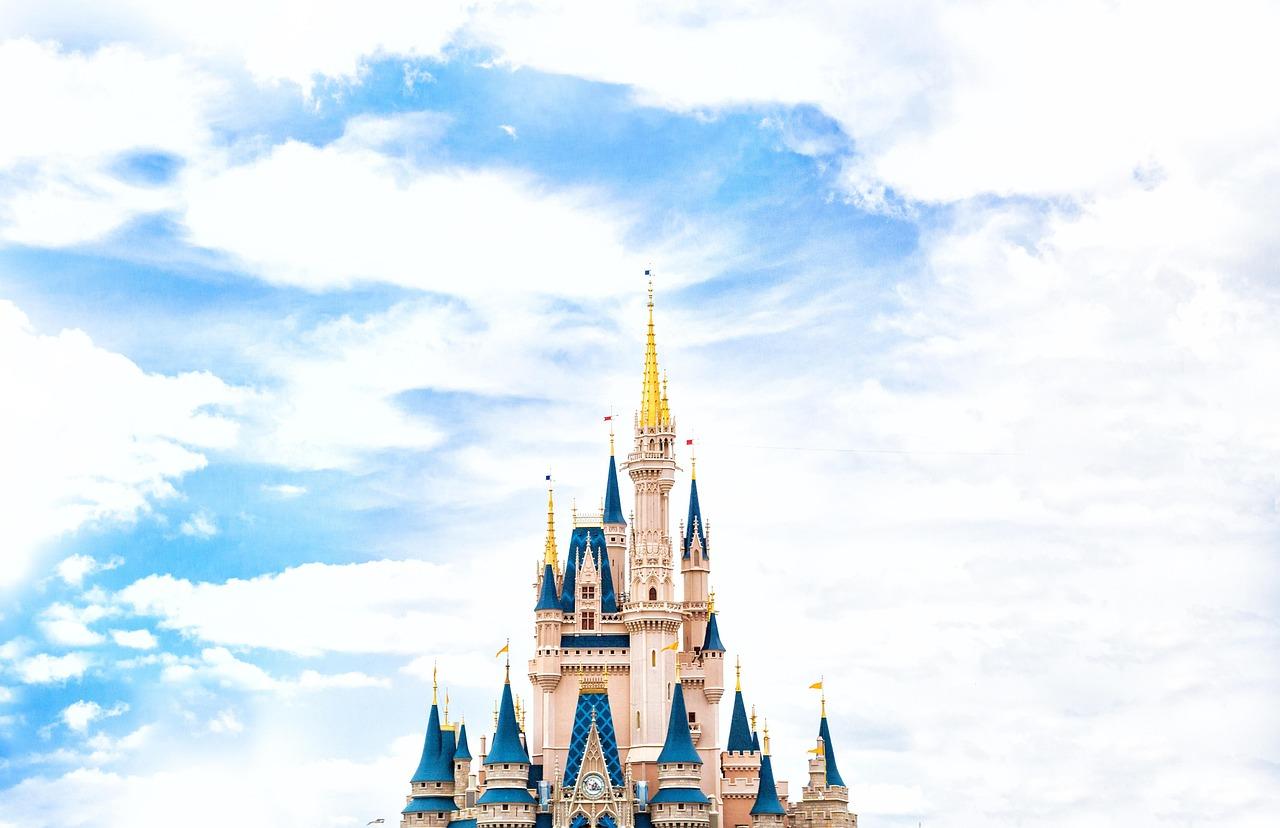 En lys og fargerik Disney-slott mot en blå himmel med spredte skyer.