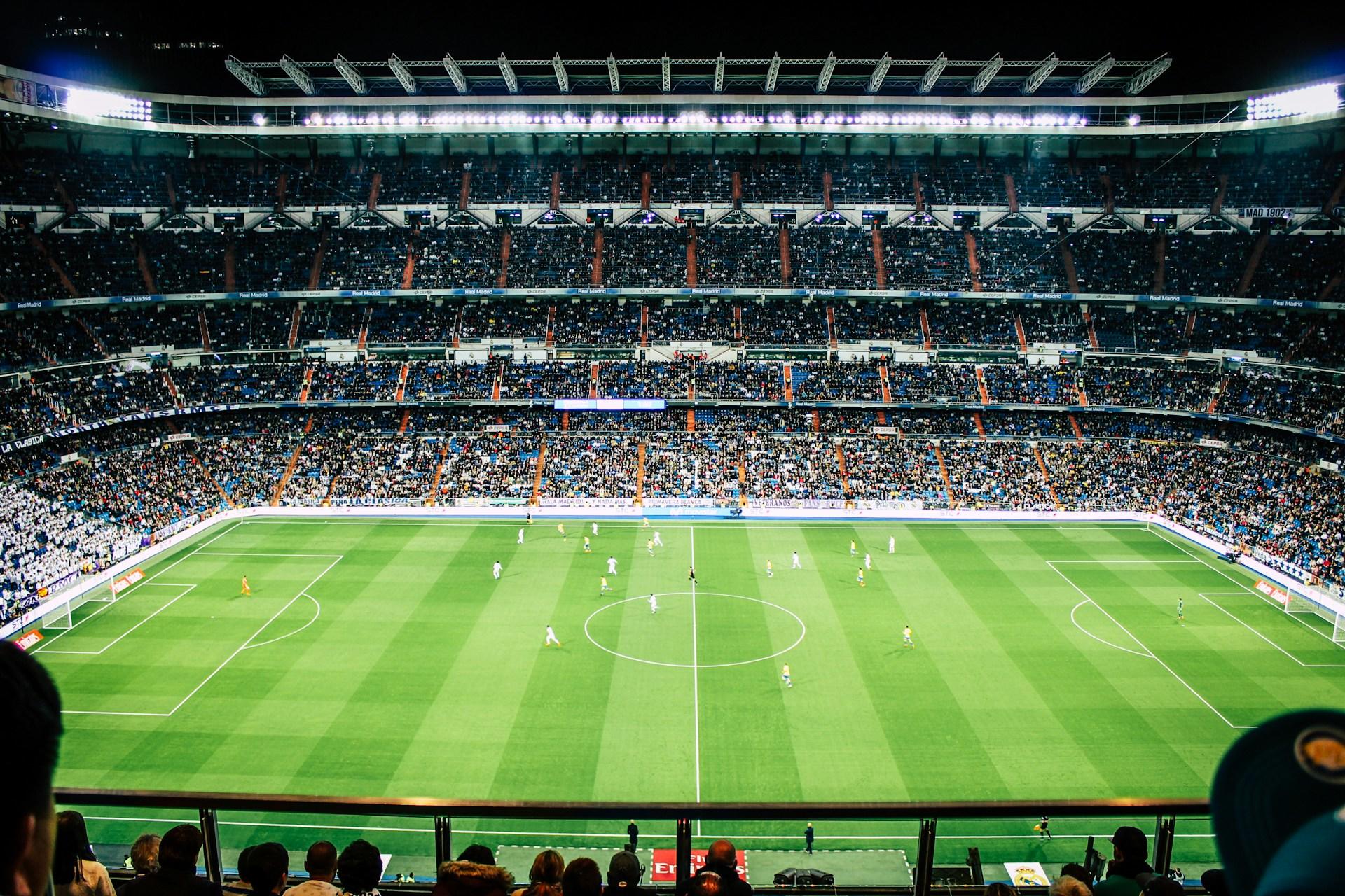 Full fotballstadion med fotballkamp på banen.
