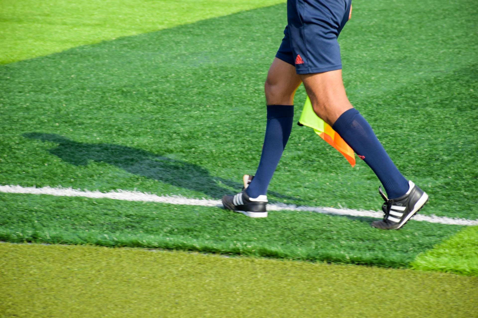 Beina på en fotballdommer som løper langs siden av fotballbanen.