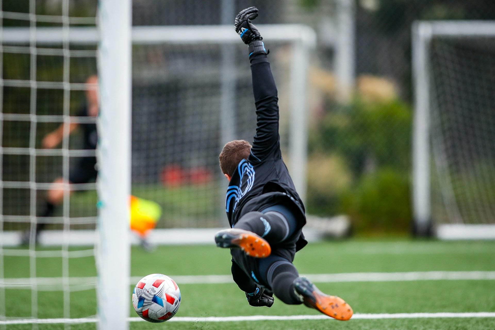 Keeper kaster seg forbi målet for å fange fotball.