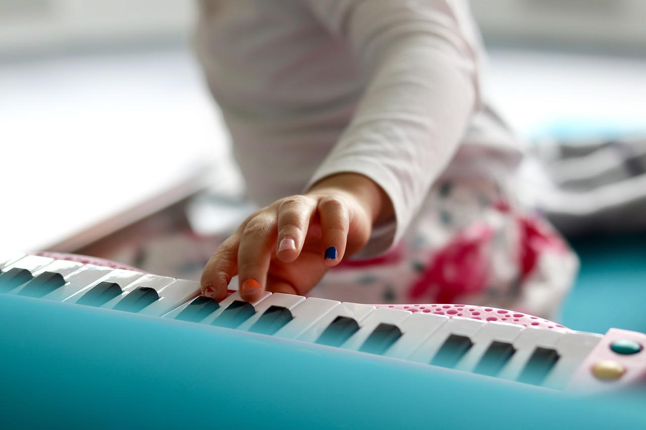 En barns hånd spiller på et fargerikt elektronisk keyboard.