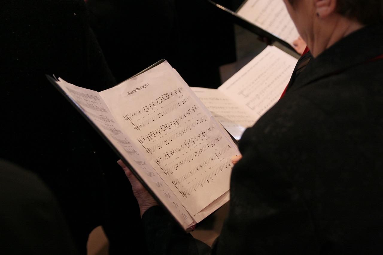 Hender som holder et åpent noteark under en korøvelse.