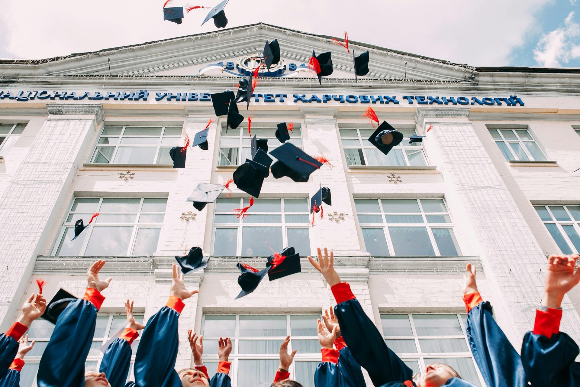 Studenter kaster "graduation cap" opp i været utenfor universitetet sitt.
