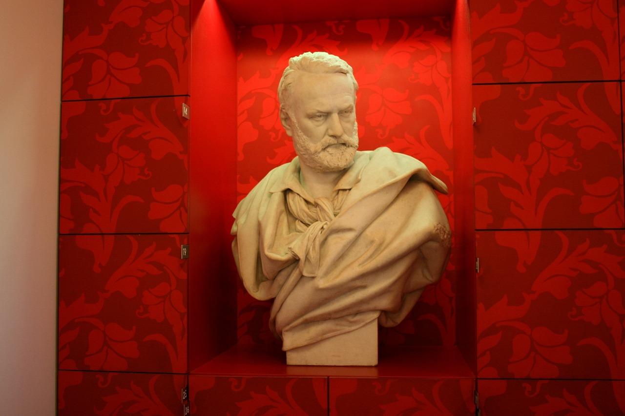 Byste av Victor Hugo foran en rød bakgrunn, symbol på hans varige innflytelse på litteraturen.