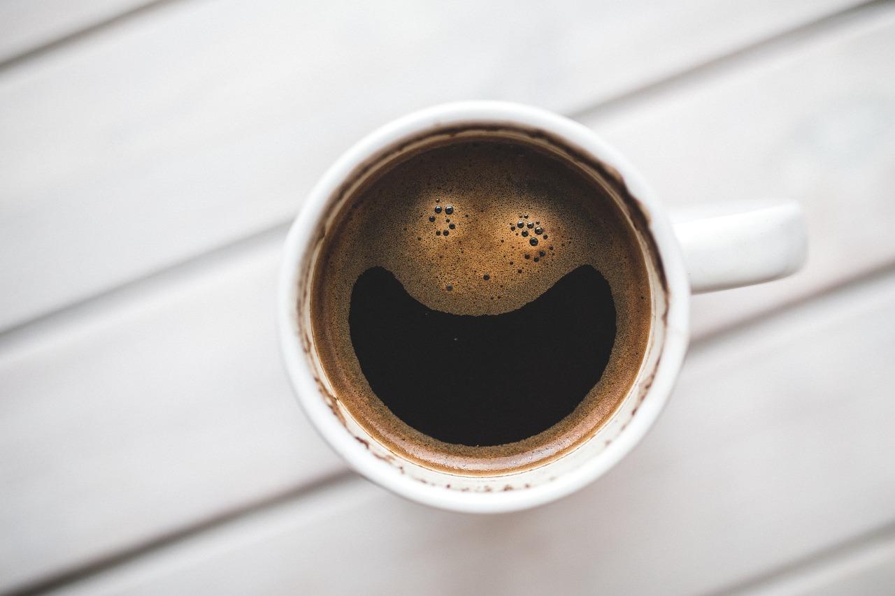 En kopp kaffe med en morsom "smilefjes" laget av kaffeskummet på overflaten.