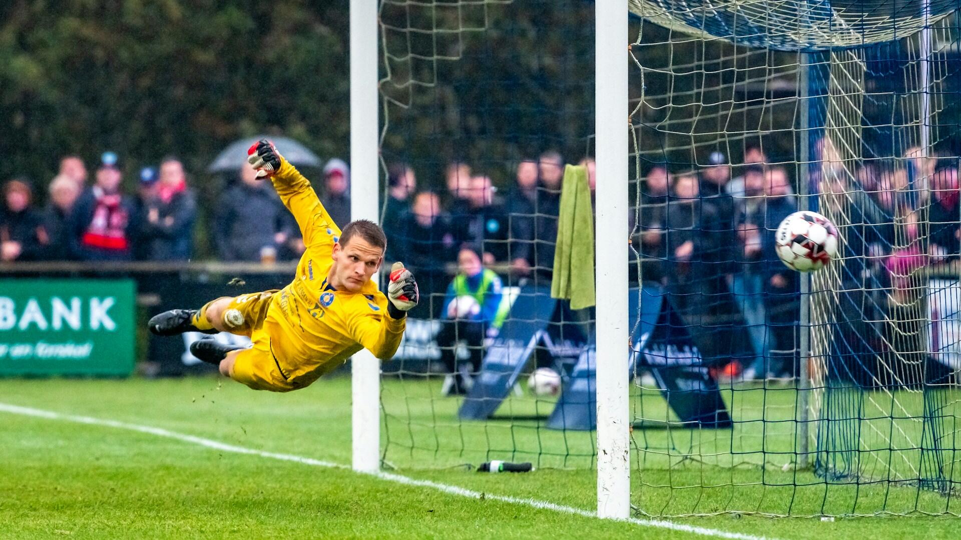 Keeper i gul drakt redder ball i mål