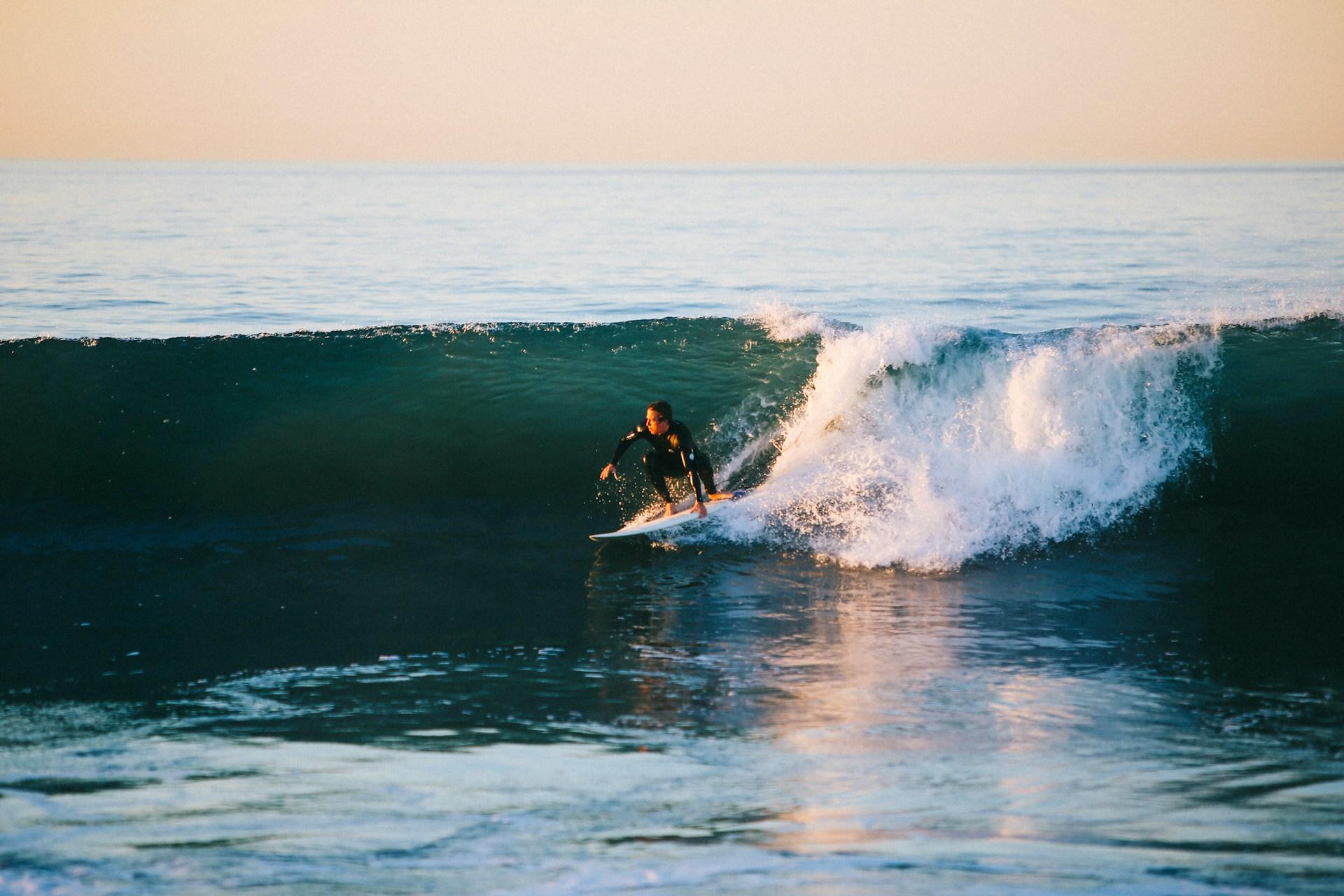 Mann surfer på bølge med våtdrakt.