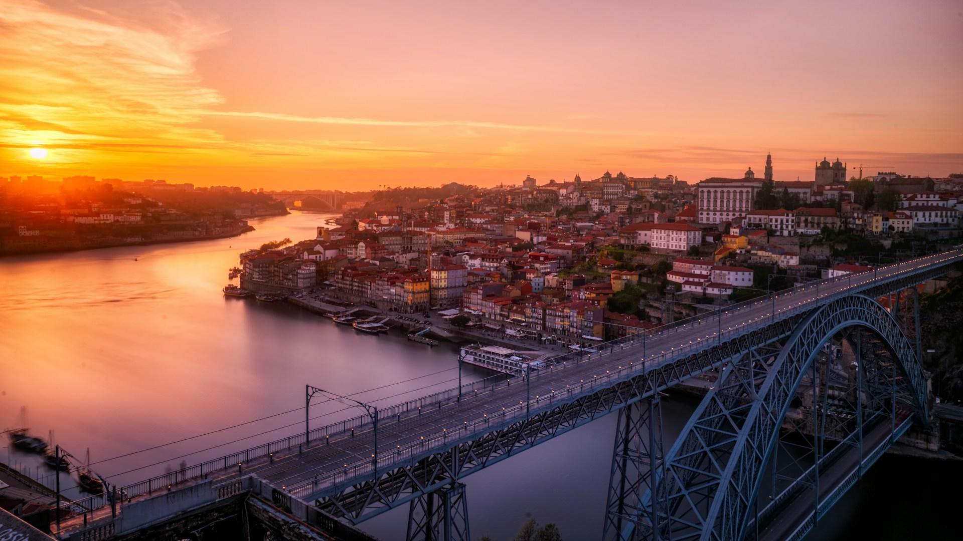 Dom Luis I broen i Portugal i solnedgang med byen i bakgrunnen.