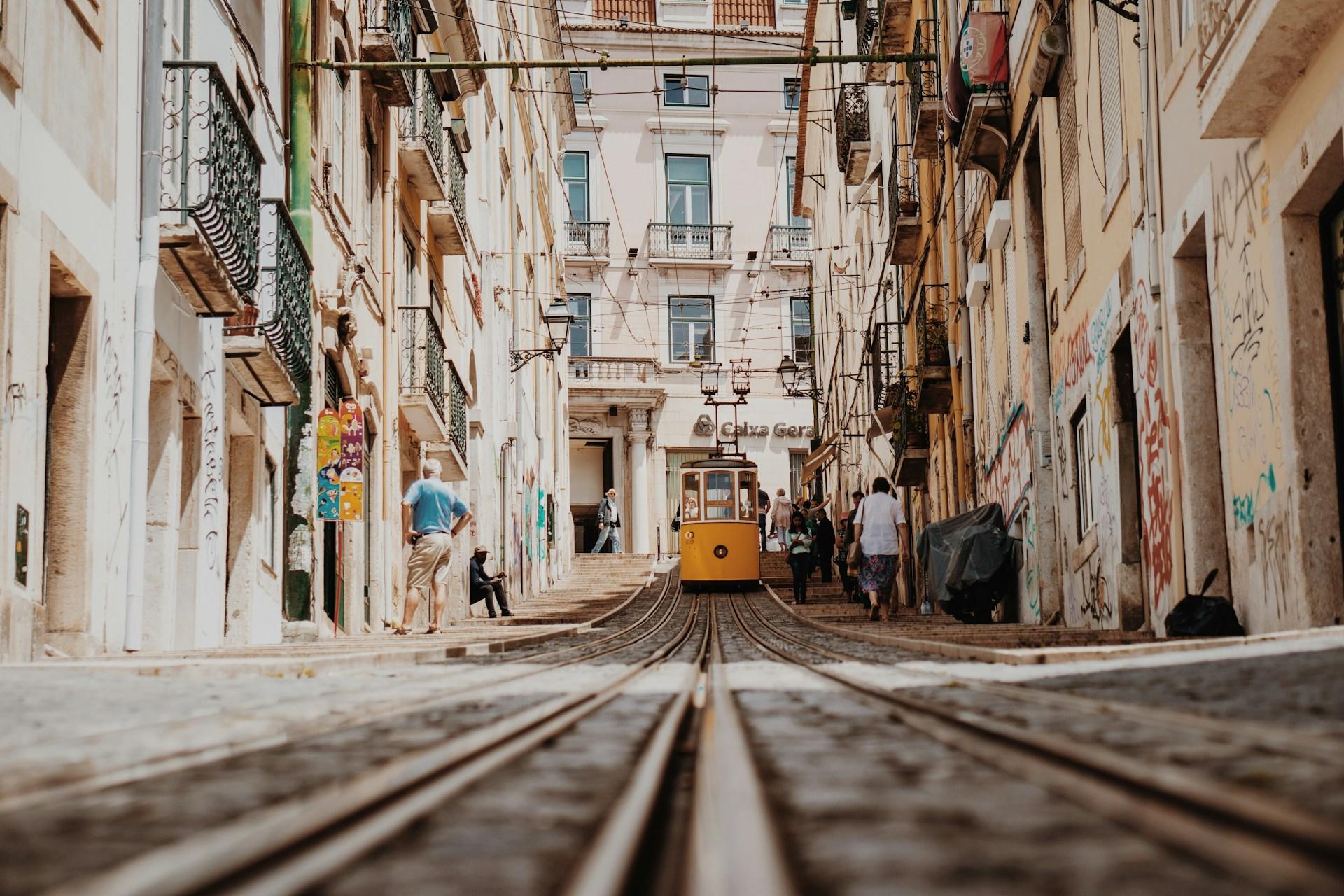 Den gule trikken i Lisboa kjører mellom gatene.