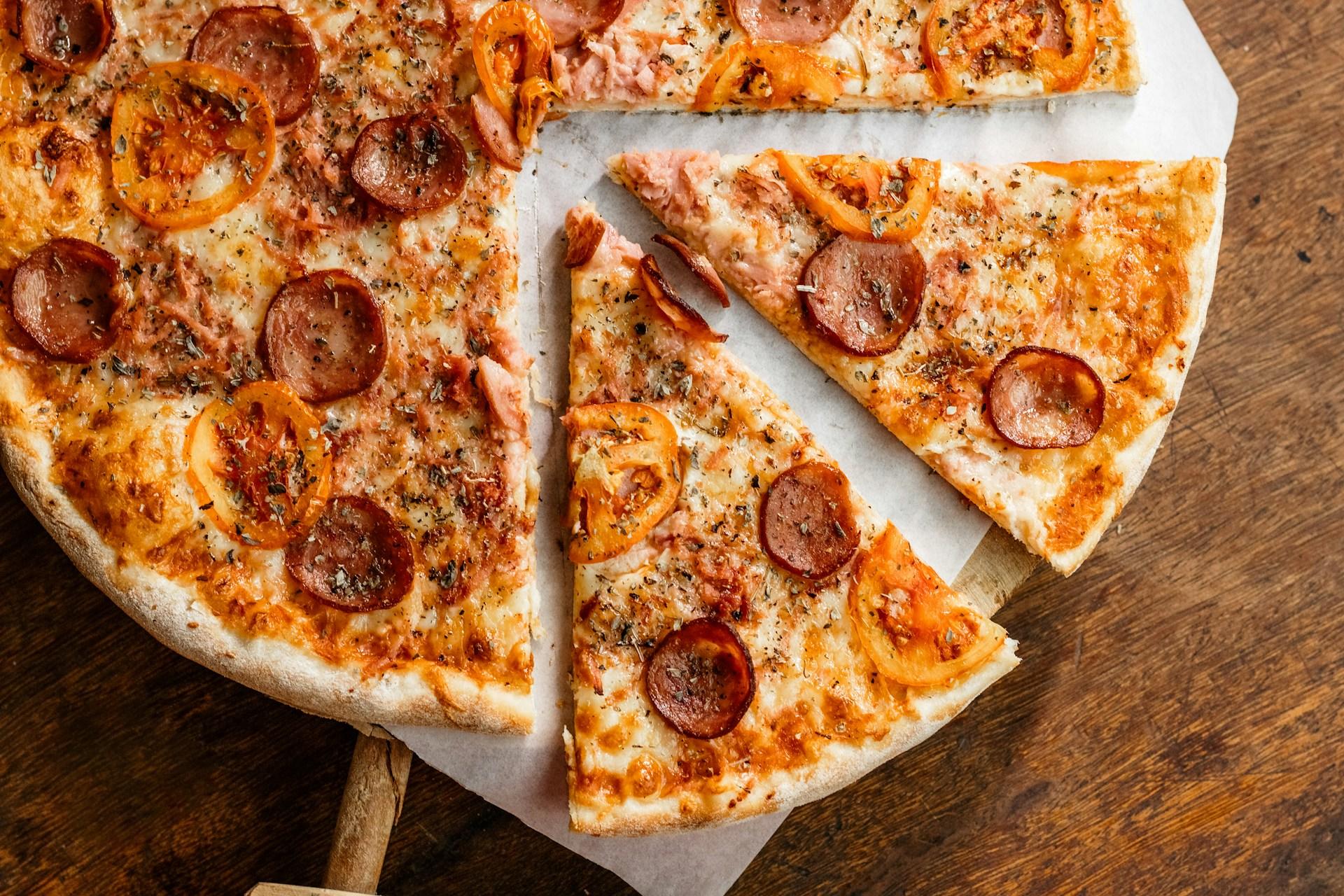 Italiensk pizza med ost og pepperoni på trebord