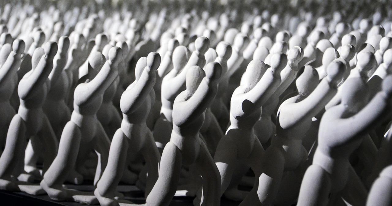 Kunstinstallasjon med mange hvite skulpturer av mennesker som marsjerer.