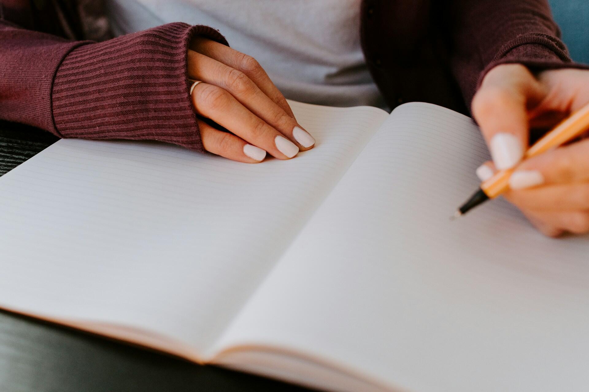 Person skriver i notatbok som del av mindfulness og stressmestrin