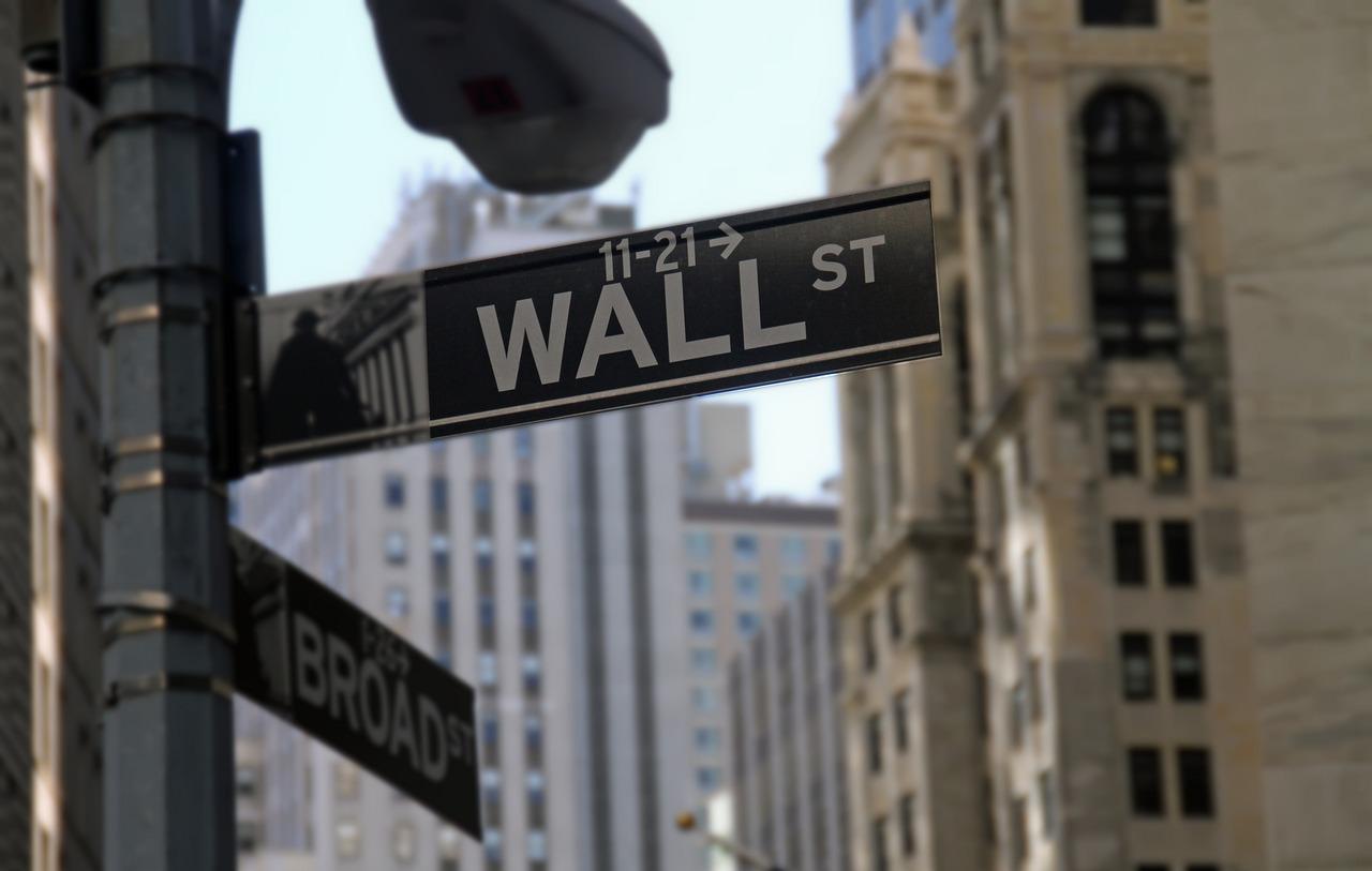 Et gateskilt som viser "Wall Street" med bygninger i bakgrunnen.