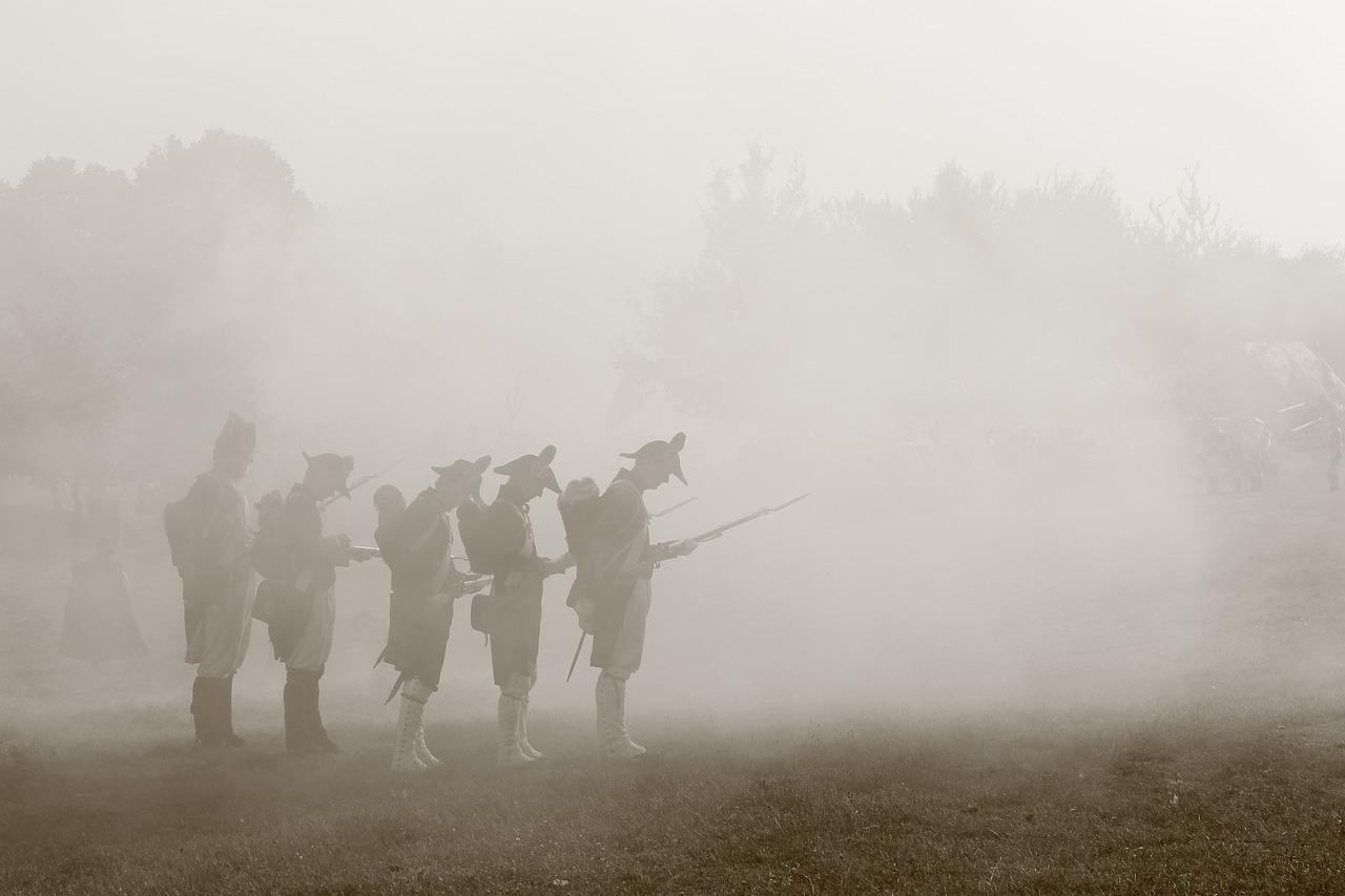 Soldater i uniformer fra Napoleons tid står i tåken, sannsynligvis under en rekonstruksjon av Slaget ved Waterloo.