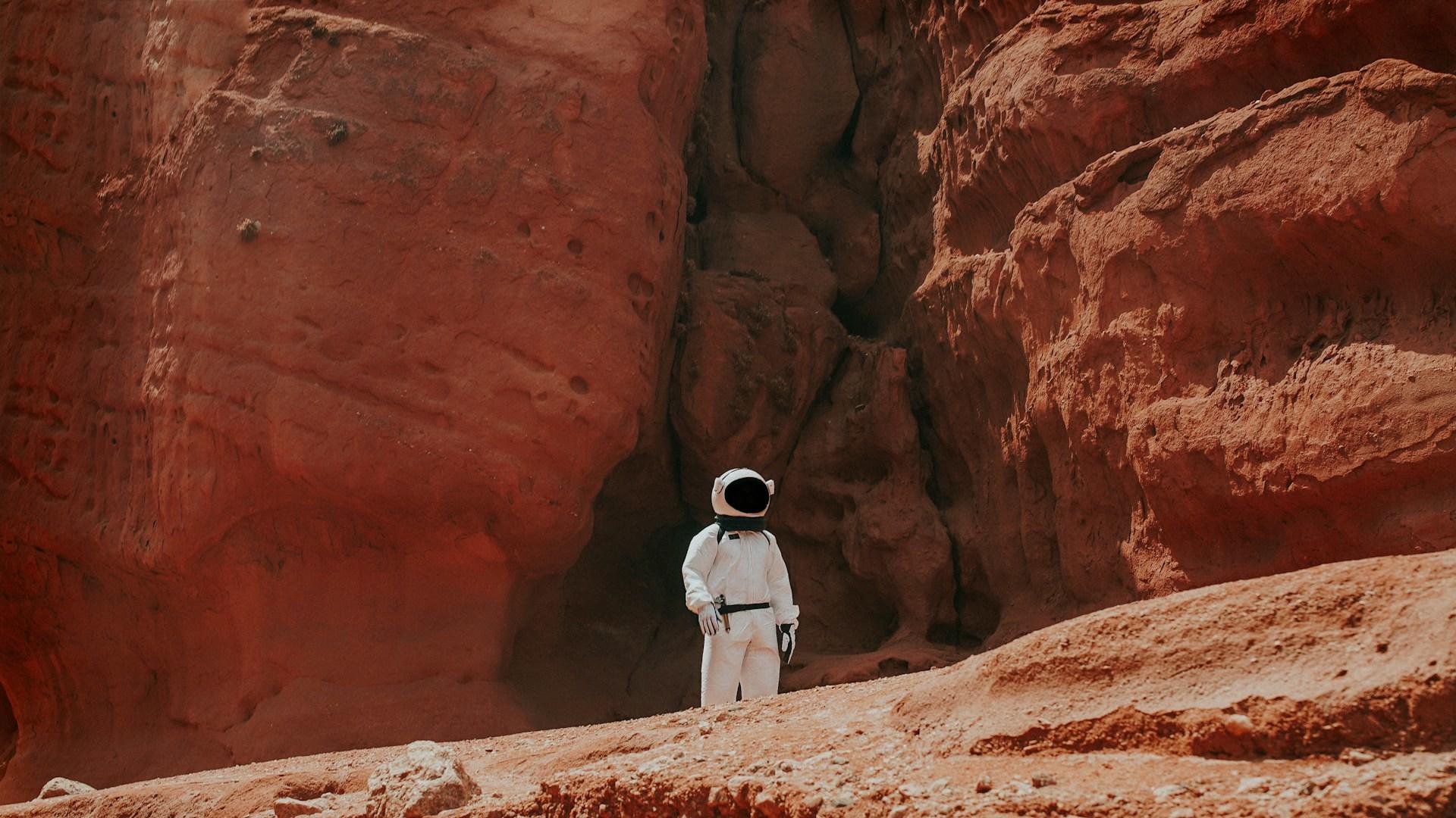 Astronaut står på rødt underlag som skal se ut som Mars.