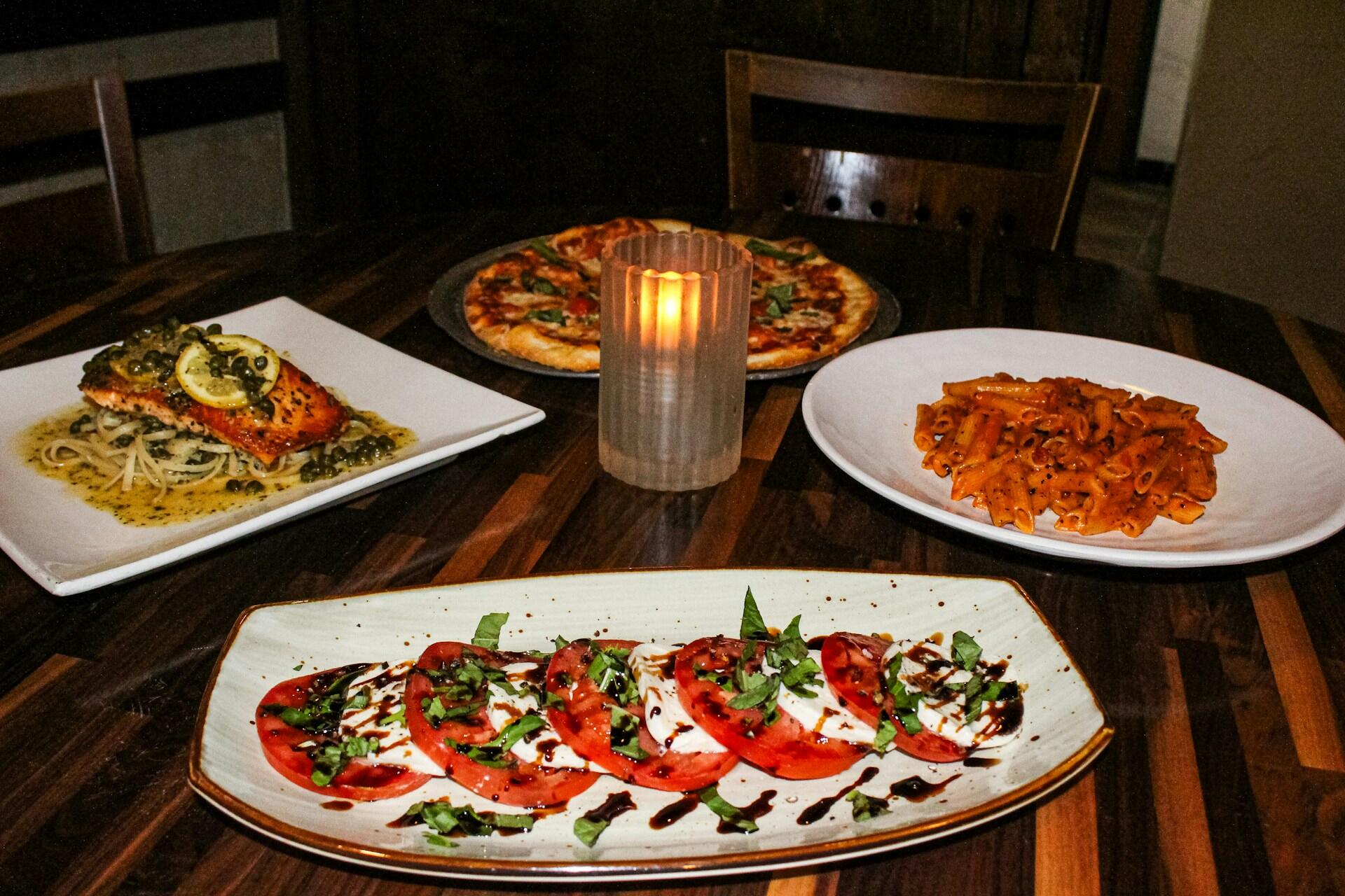Caprese-salat med tomater, mozzarella og basilikum, servert med pasta, fisk og pizza på italiensk restaurant