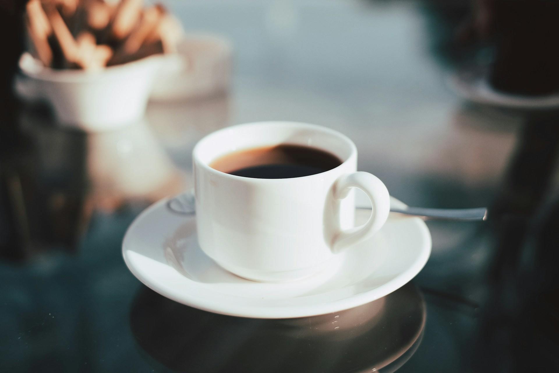 Hvit kaffekopp med skje og tallerken.