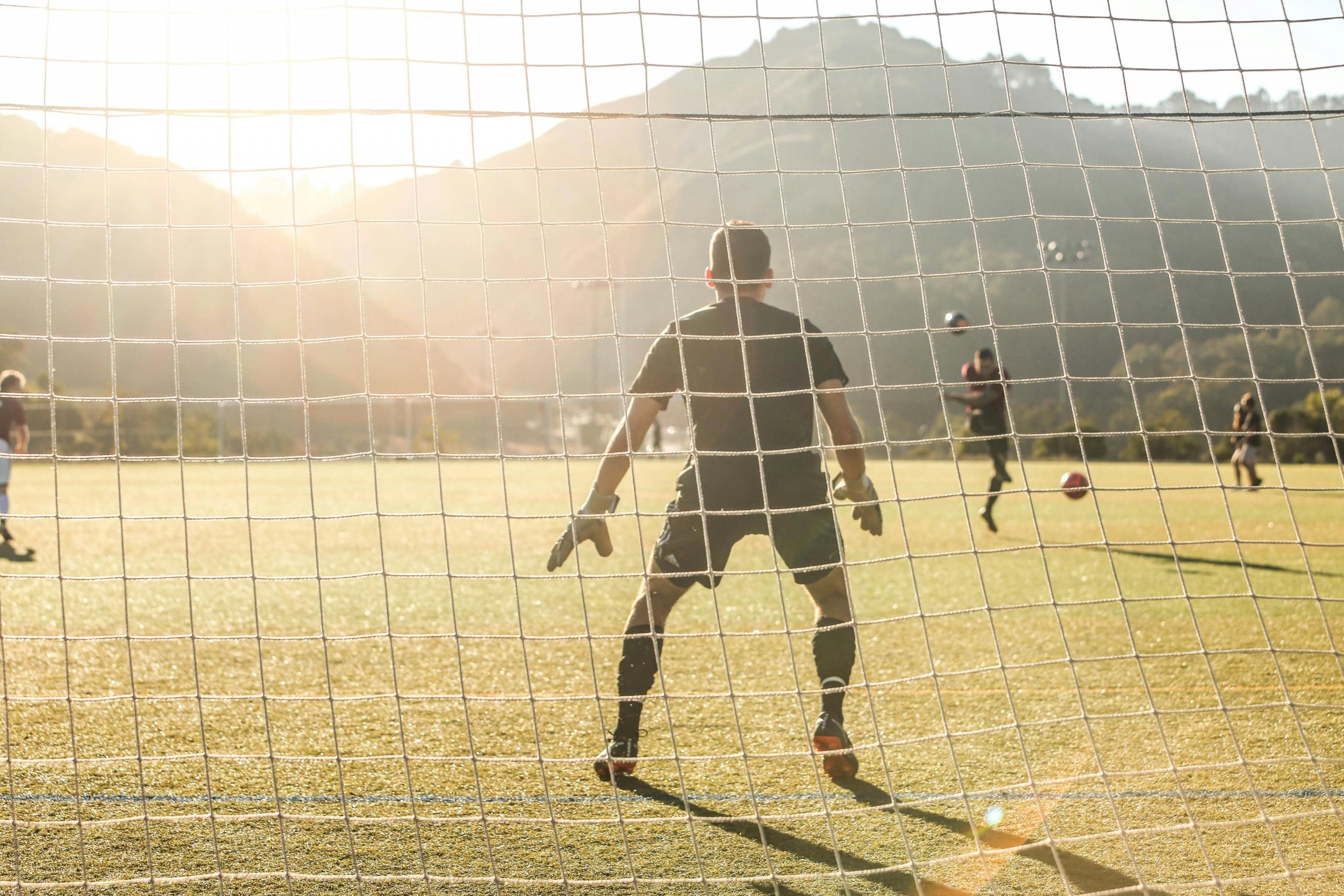 Keeper som står klar foran målet under en solfylt fotballtrening.