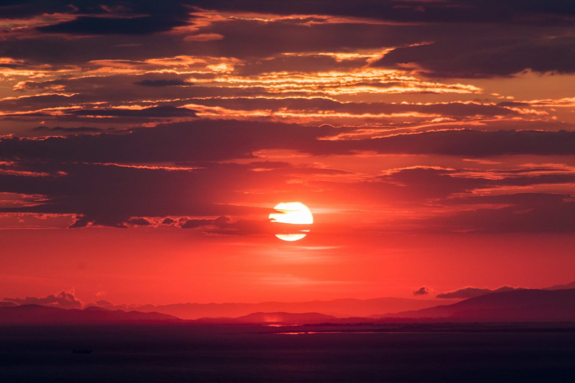Rød solnedgang med skyer.
