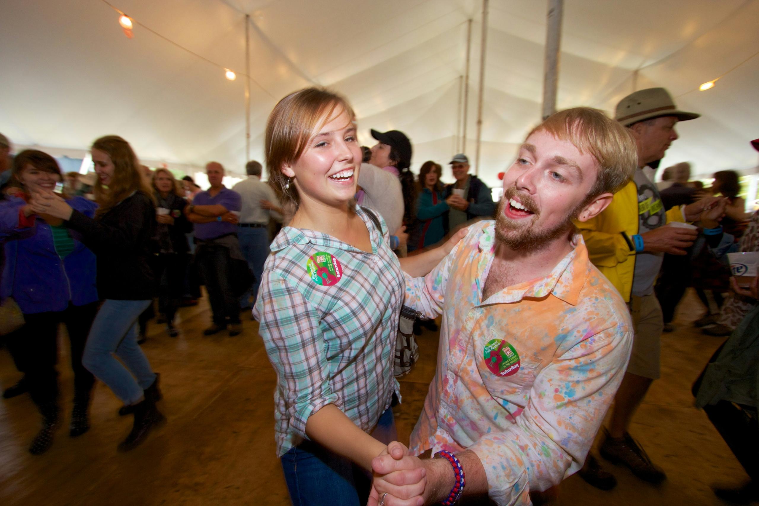 Et ungt par danser en tradisjonell norsk dans under en folkefest.