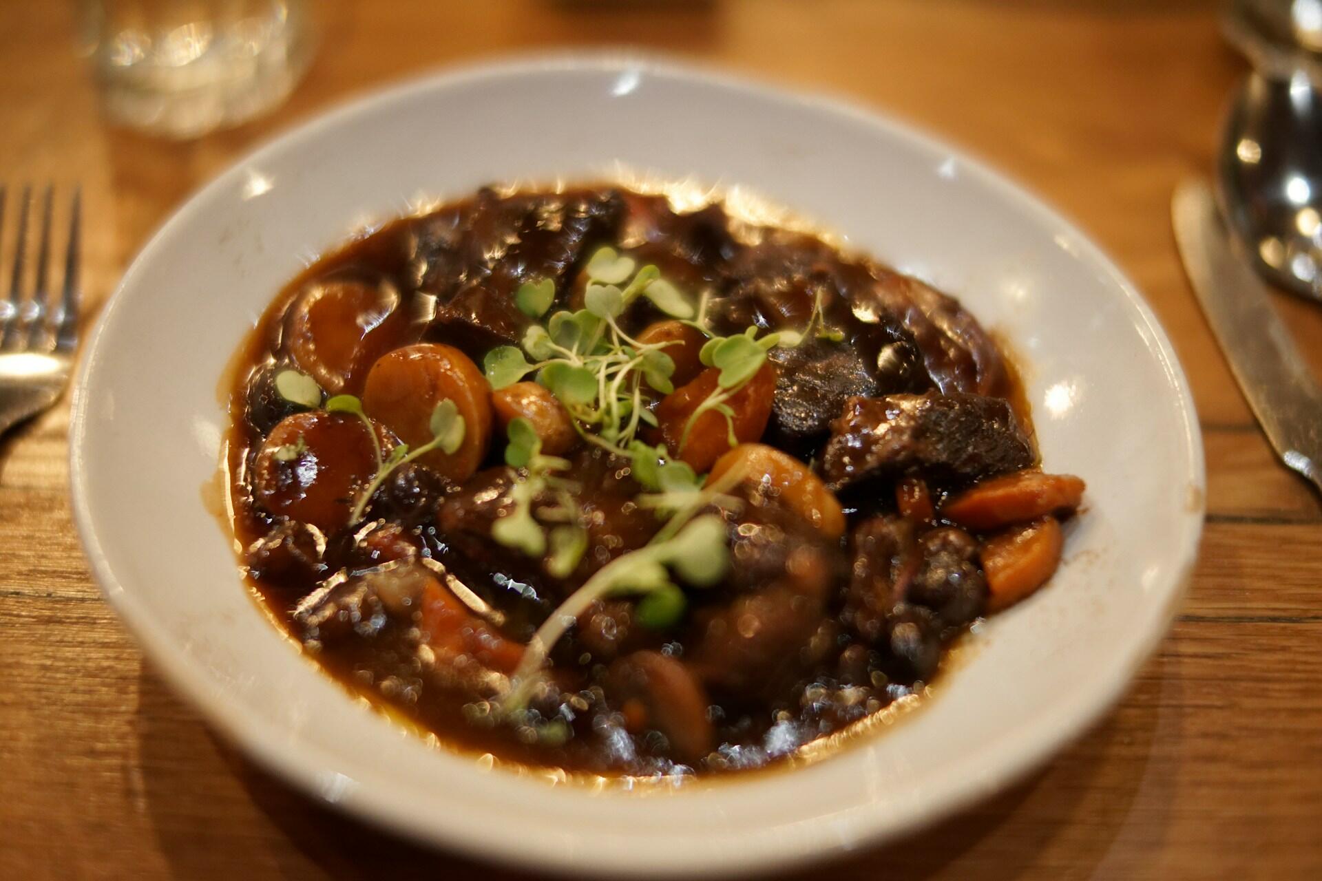 Coq au vin med kylling, grønnsaker og urter i en fyldig rødvinssaus.