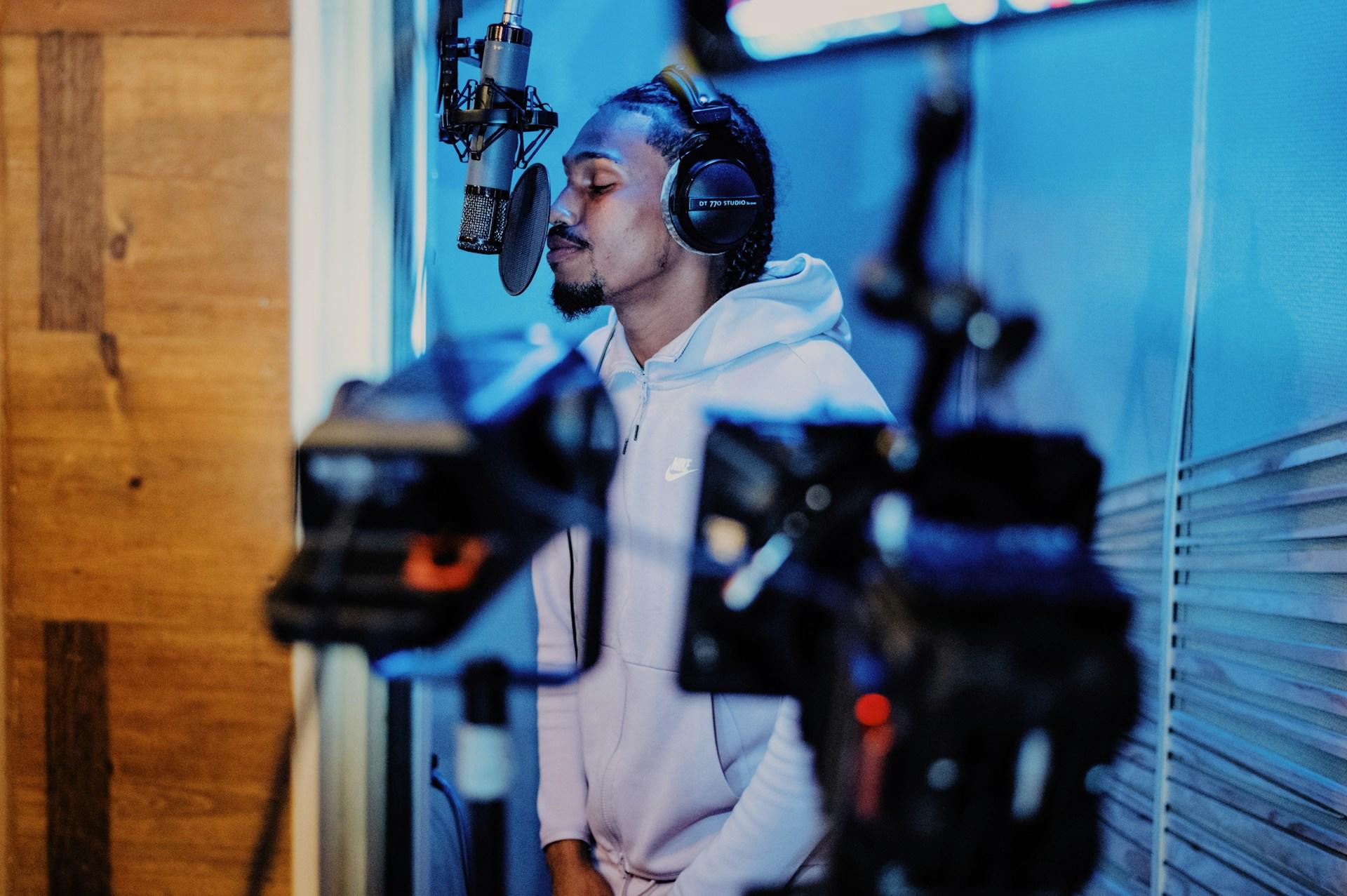 Mann står i studio med hodetelefoner og synger inn i mikrofon.