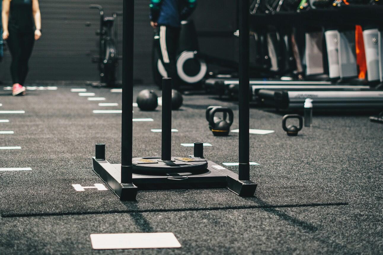 Treningsutstyr som vekter og kettlebells på treningsstudioets gulv.