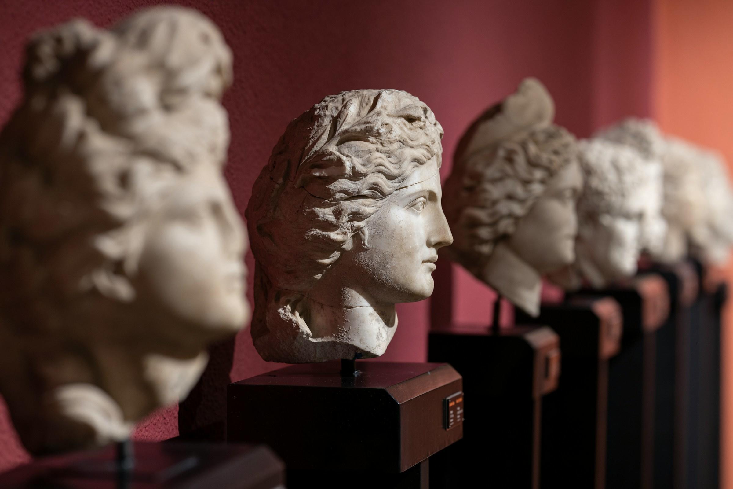 Historiske statuer som står bortover utstilt på et museum.