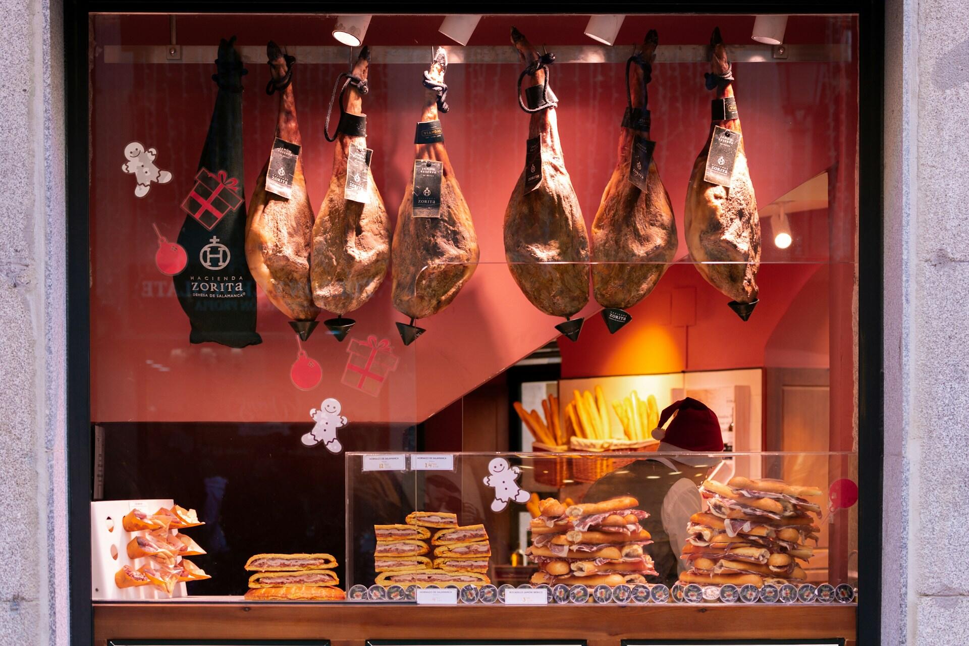 Et butikkvindu med spansk skinke (jamón serrano) og ferske baguetter. En klassisk del av den spanske matkulturen.