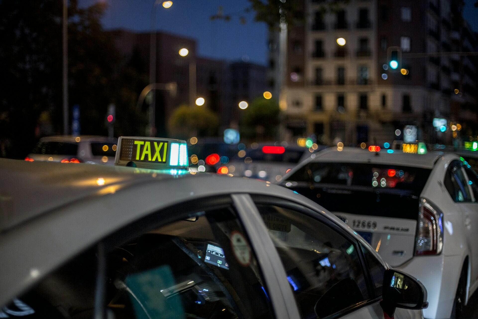 En opplyst taxibil i en travel spansk by om kvelden, ideell for å illustrere transport og kommunikasjon i hverdagen på spansk.