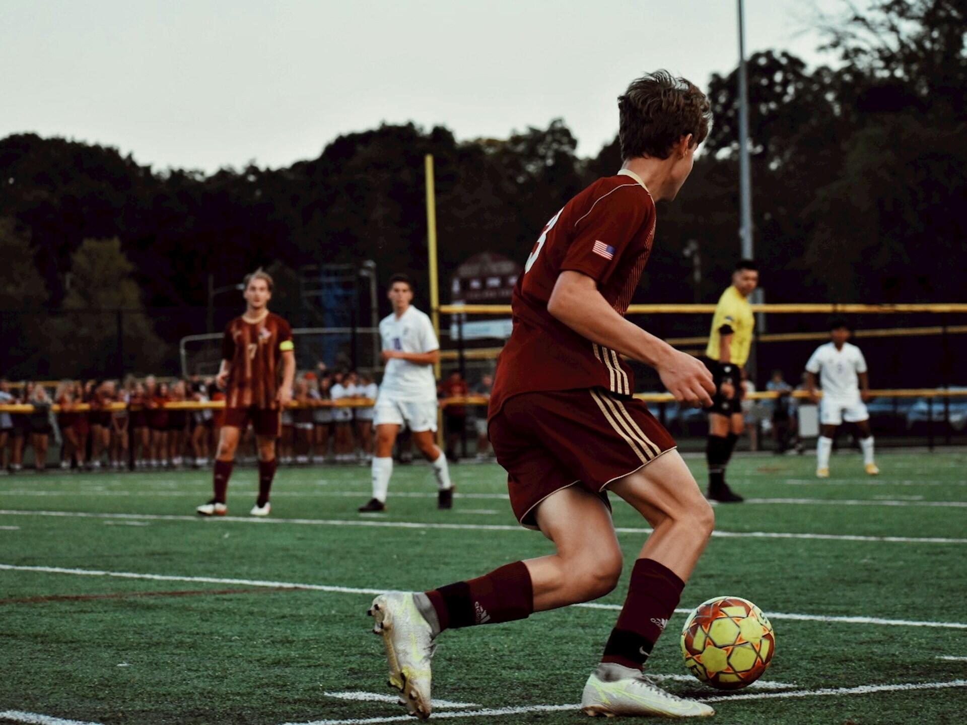 Dommer i fotballkamp med fotballspiller som skal sparek gul fotball