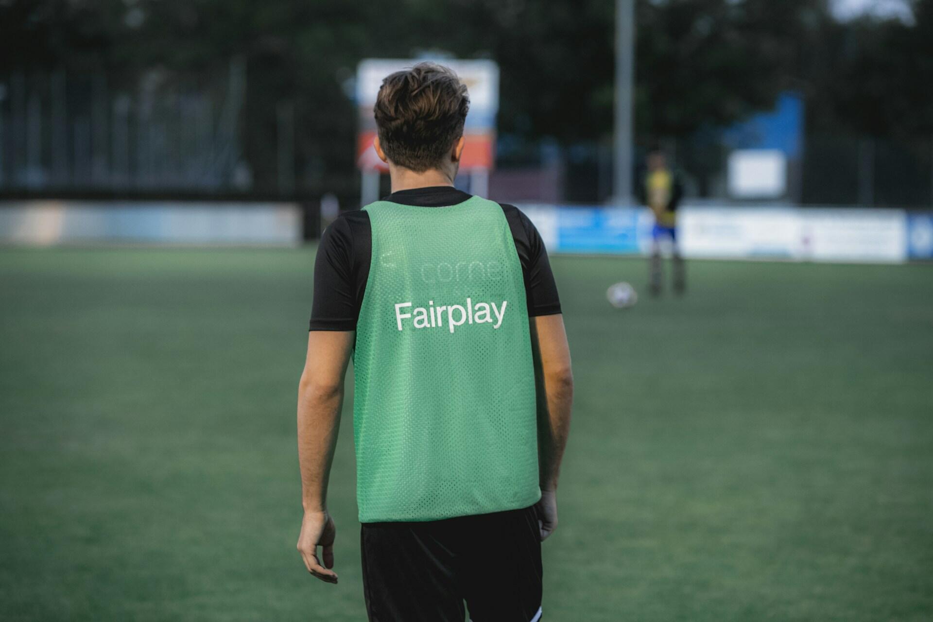 Fairplay står på baksiden av manns fotballtrøye som er på en fotballbane