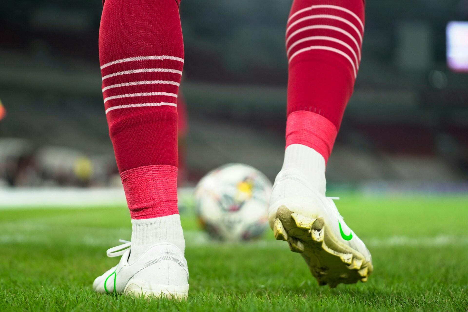 Fotballspiller nederste del av legger med rød sokker på.