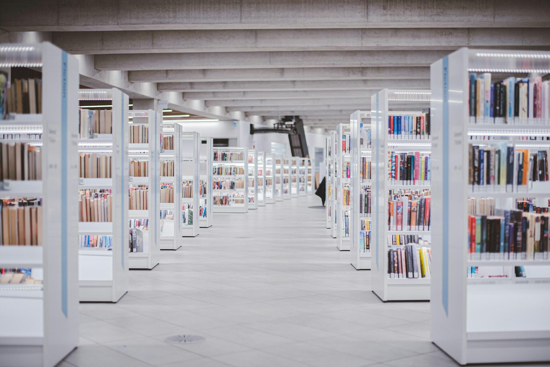 Lyse bokhyller i et moderne bibliotek med åpne gangveier.