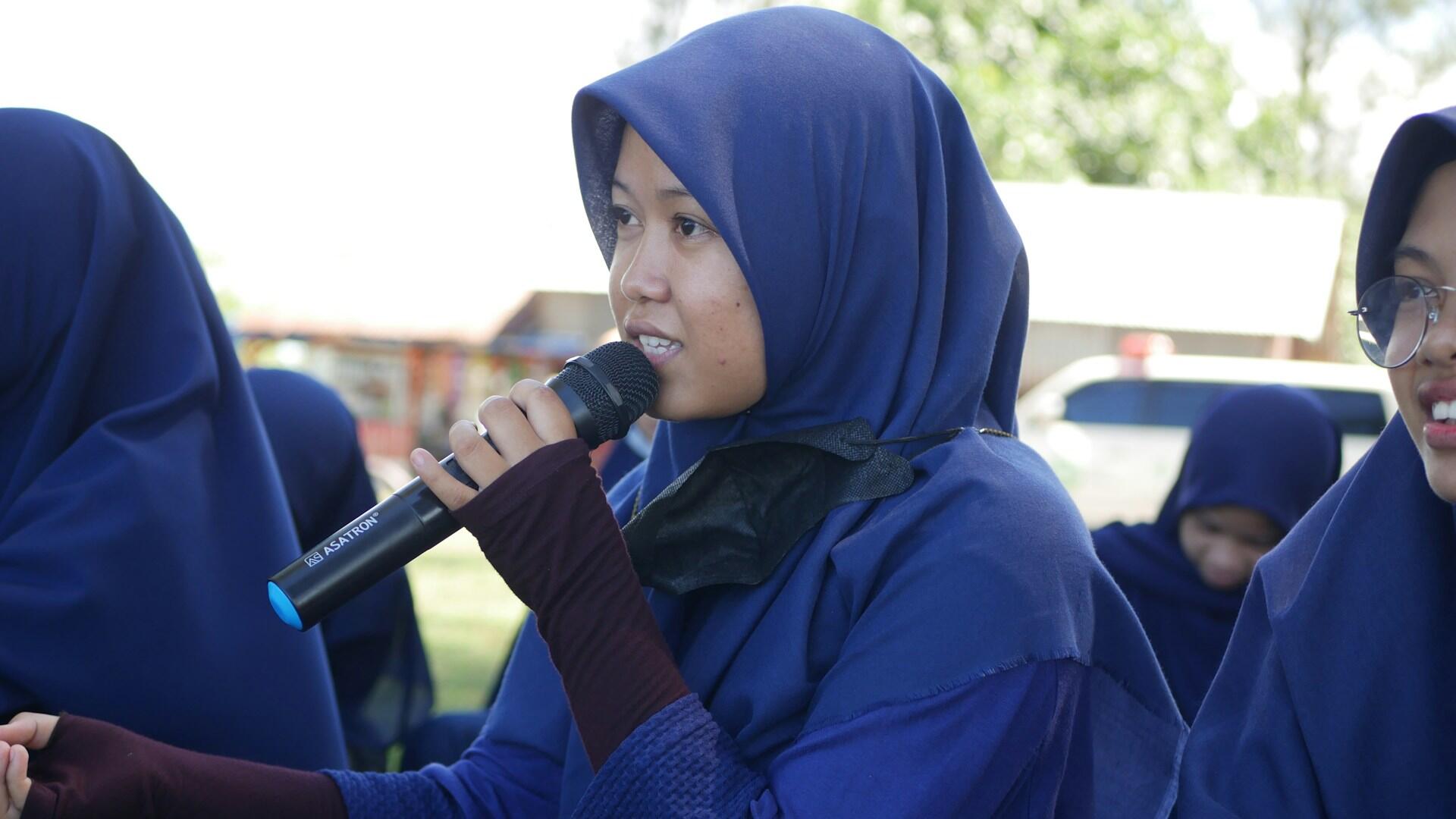 Ung kvinne med hijab snakker i mikrofon under tale