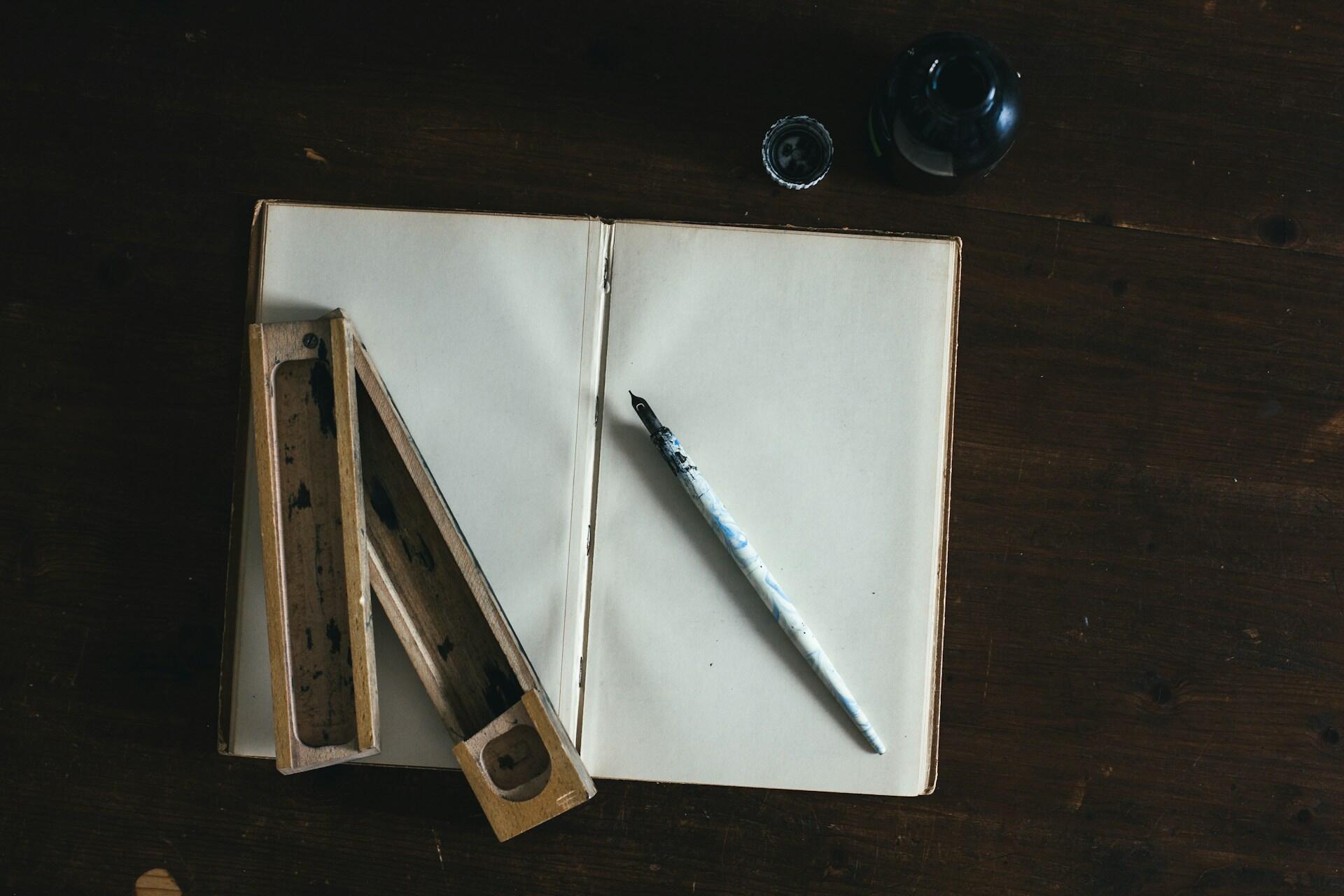 En åpen notatbok og en fjærpenn ligger på et skrivebord, klare til å skrive en tale.