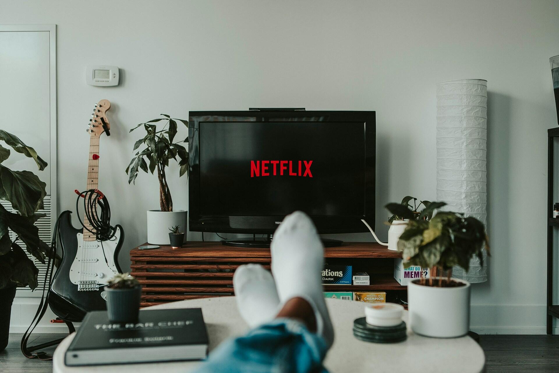 Bein på bordet foran en tv-skjerm med Netflix logo på.