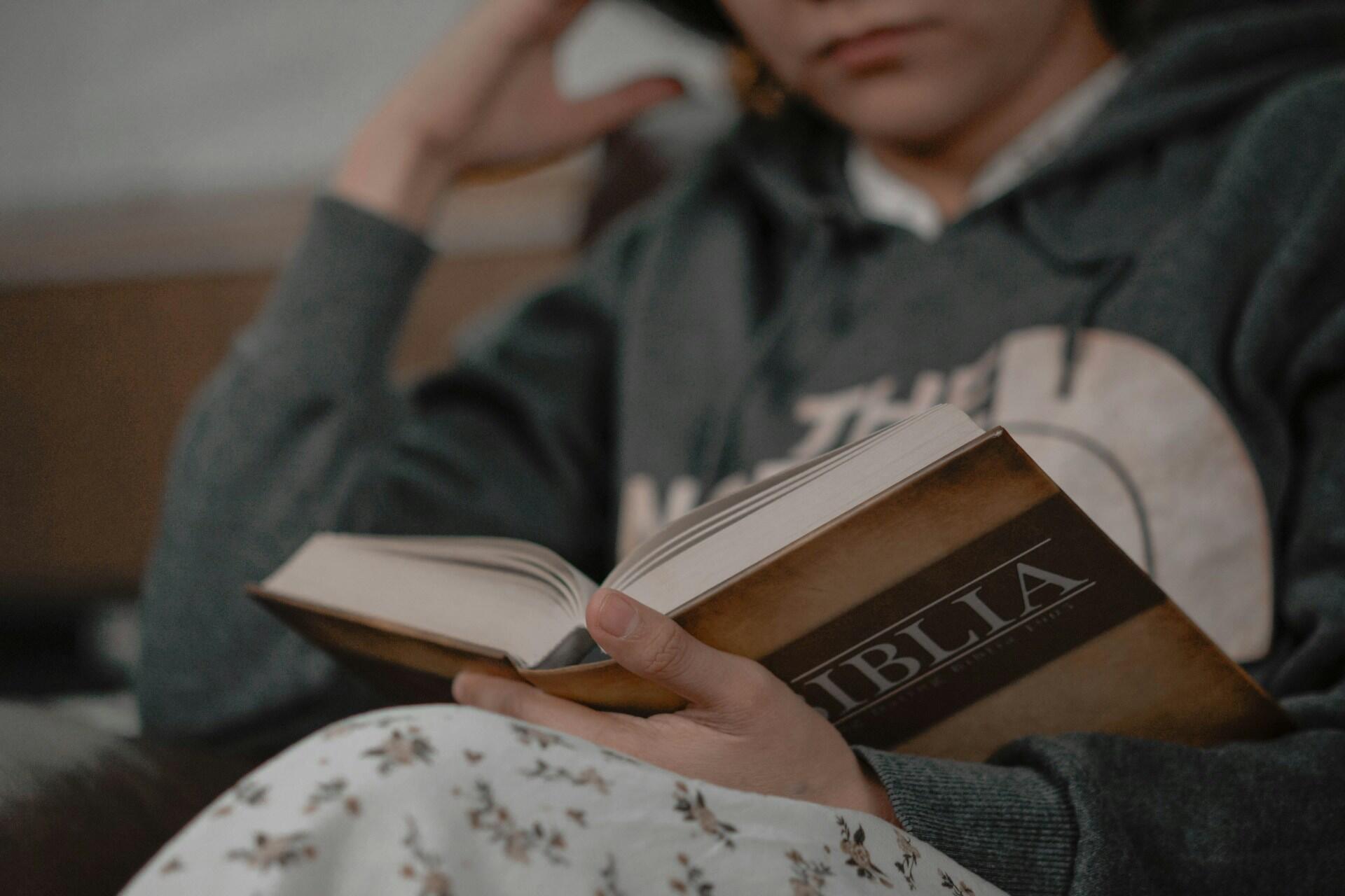 Gutt sitter komfortabelt og leser bok for gode norske lesevaner