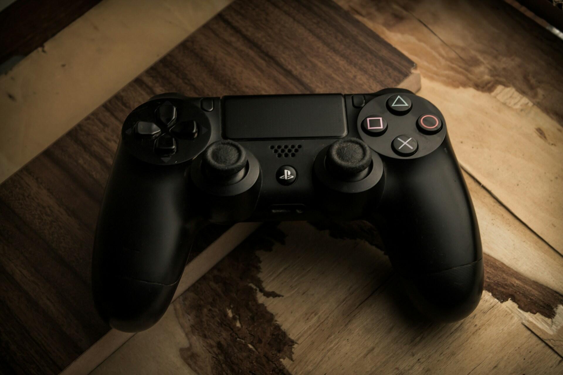Kontroller til Playstation ligger på trebord.