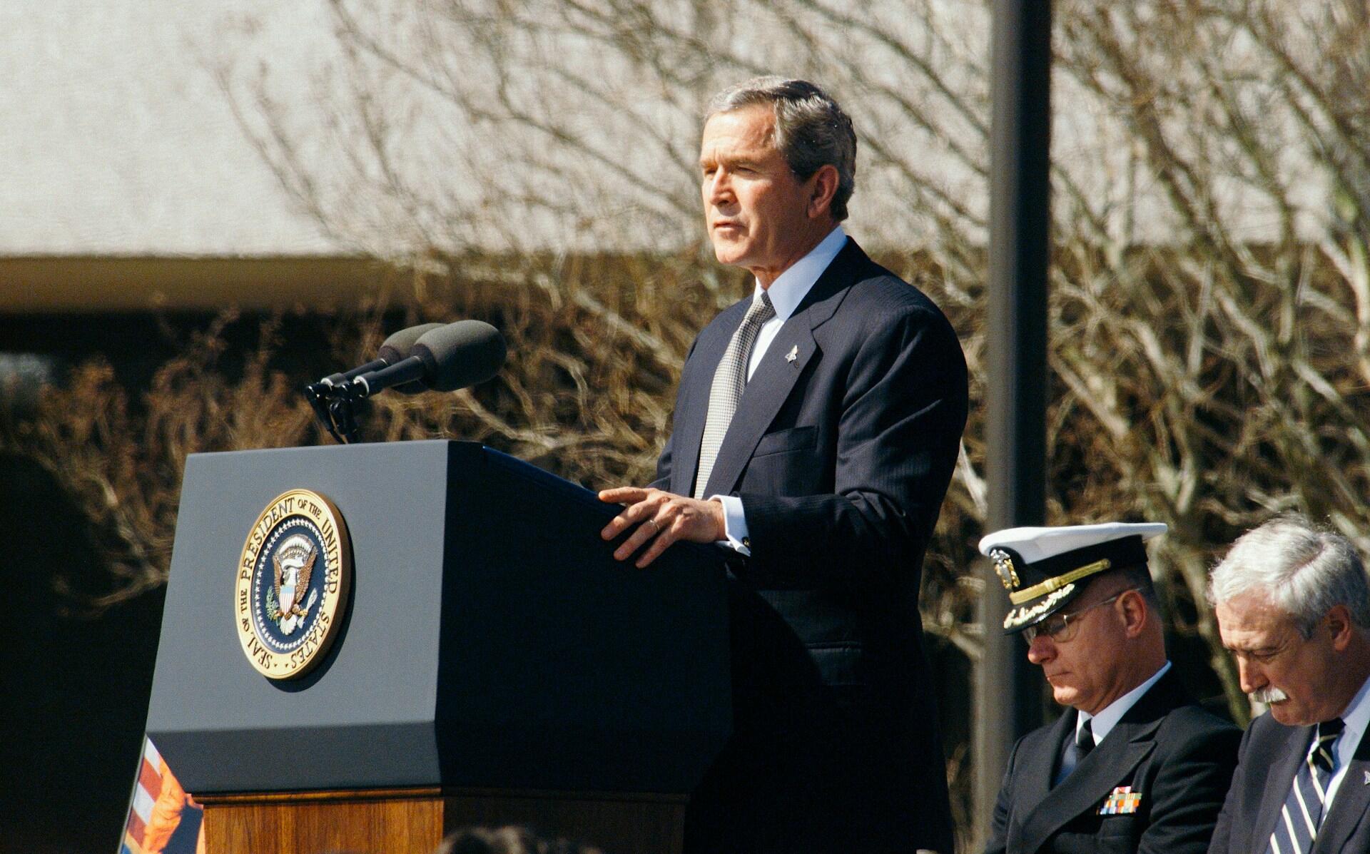 George W. Bush holder en tale på en talerstol, med presidentens segl i bakgrunnen.