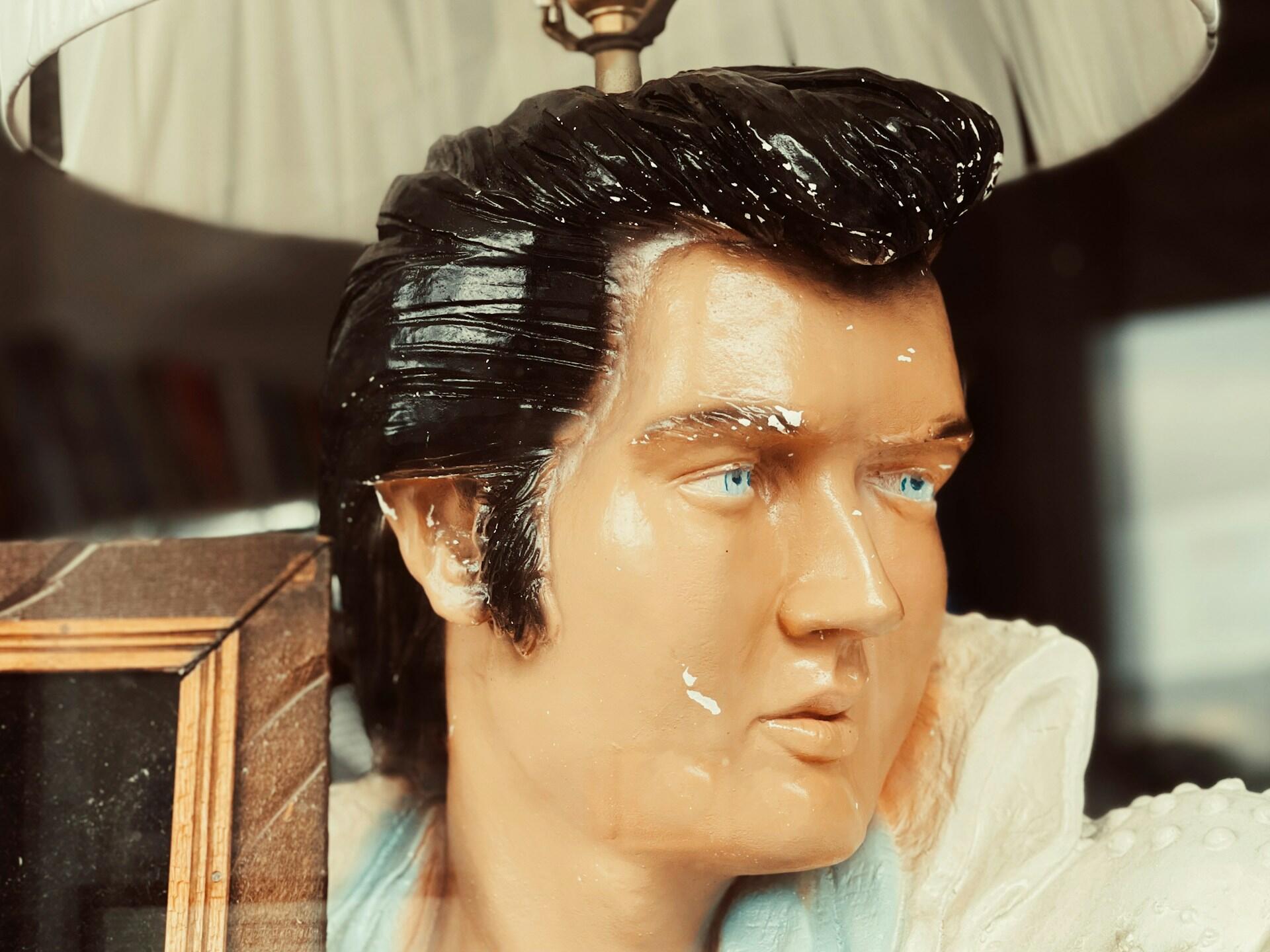 Nærbilde av Elvis Presley-statue med blå øyne og karakteristisk frisyre.
