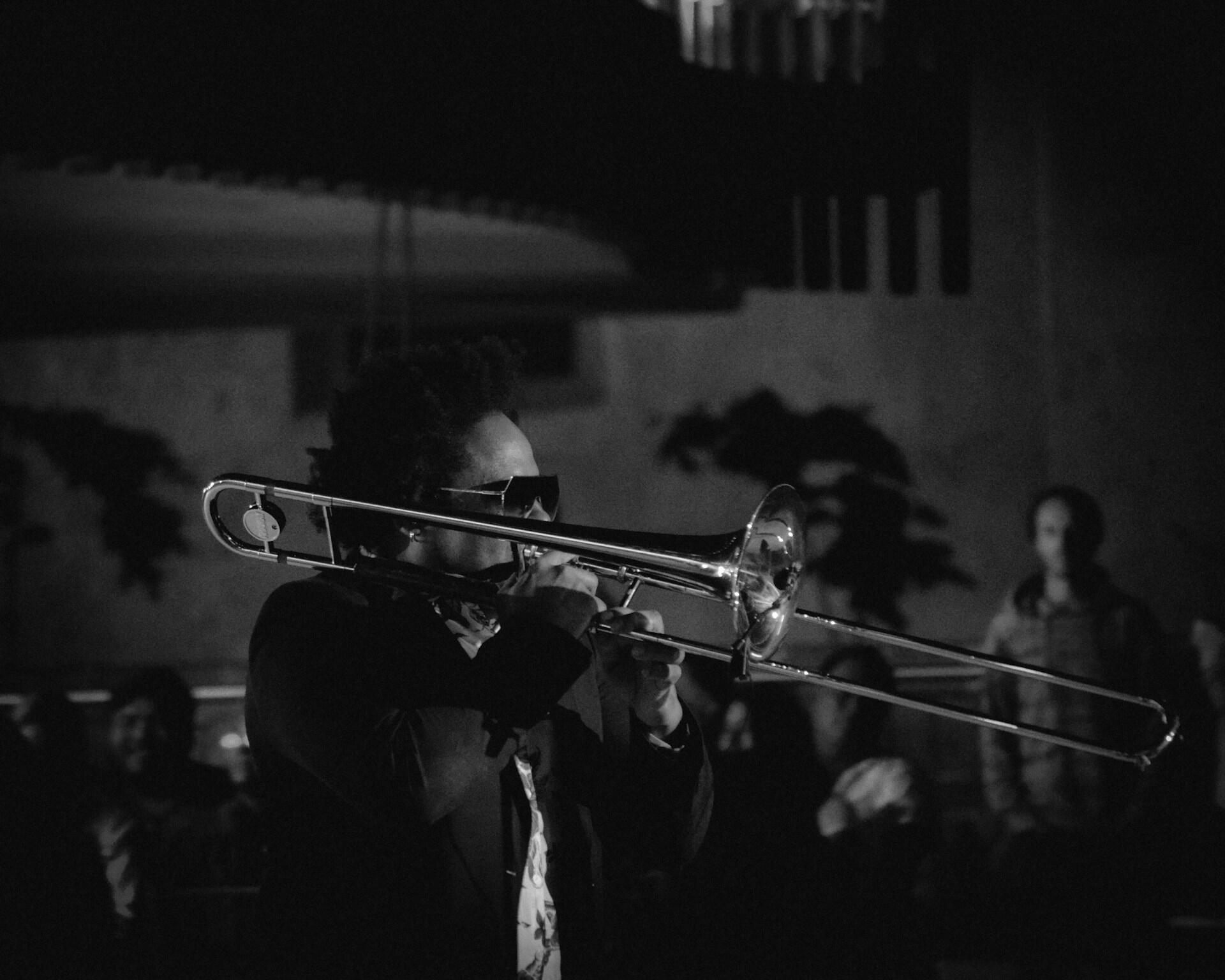 Svart-hvitt-bilde av jazzmusiker som spiller trombone foran publikum.