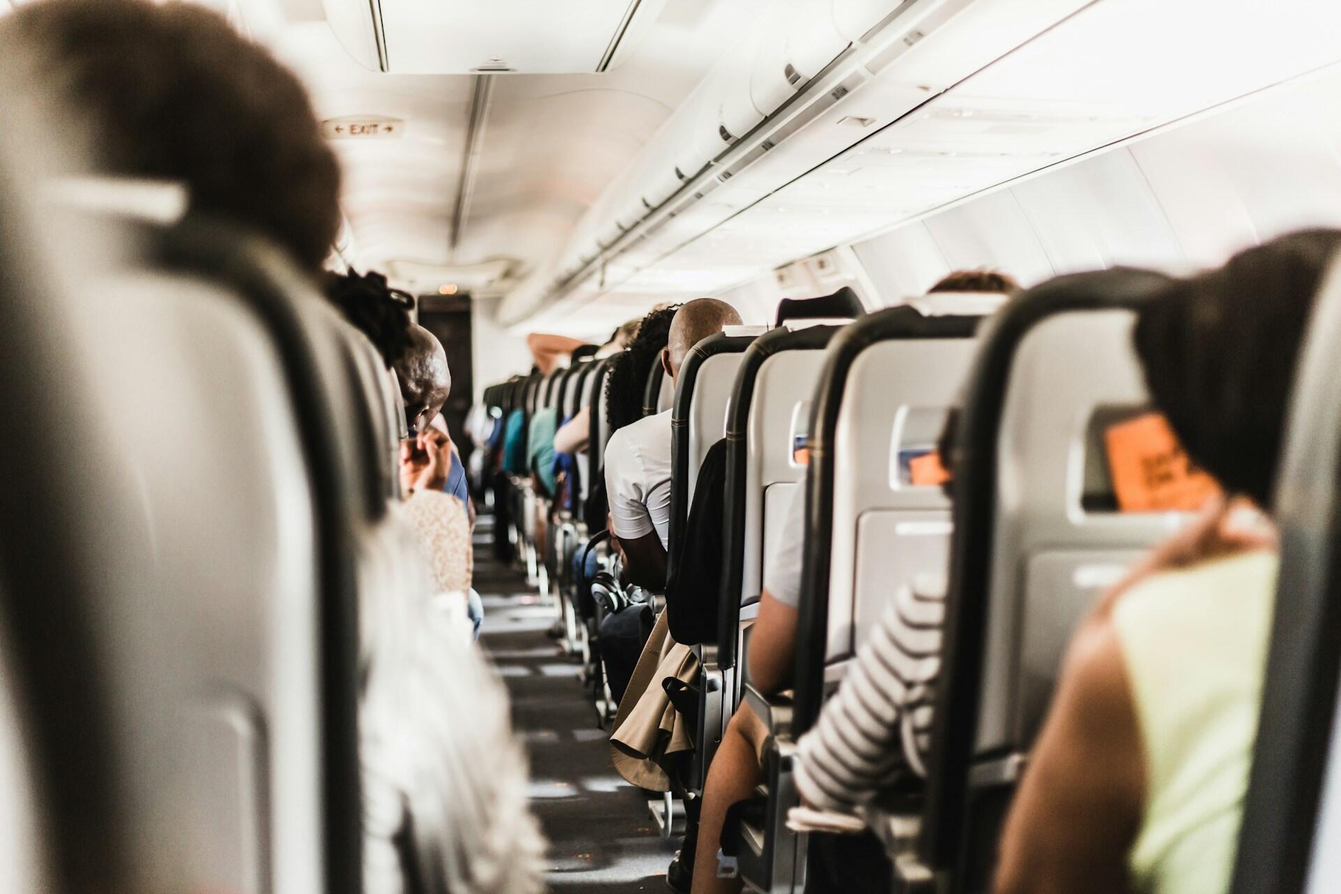 Mennesker som sitter på rekke og rad på fullt fly.