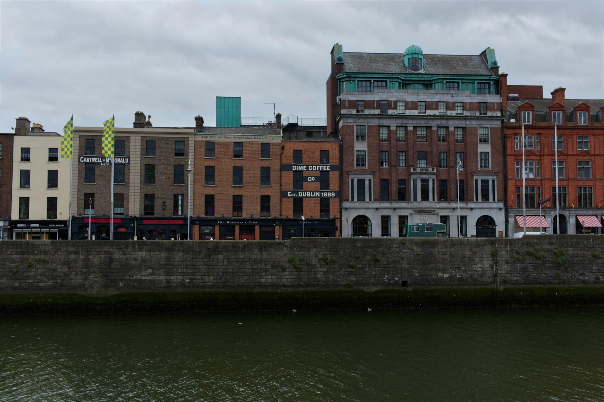 Fasade med kaffebar og historiske murbygninger ved elven i Dublin sentrum.