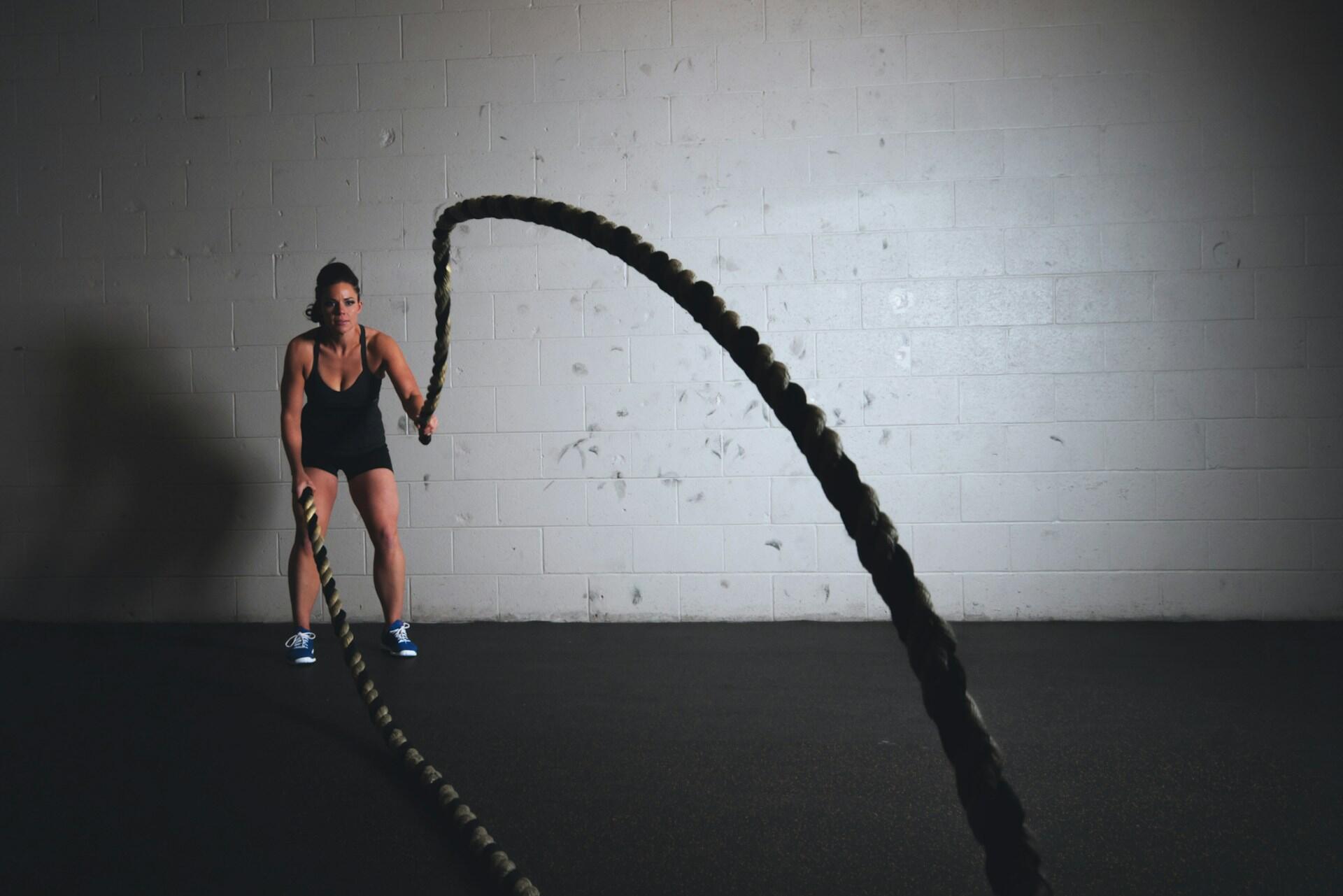 Kvinne trener med battle ropes i et treningsstudio
