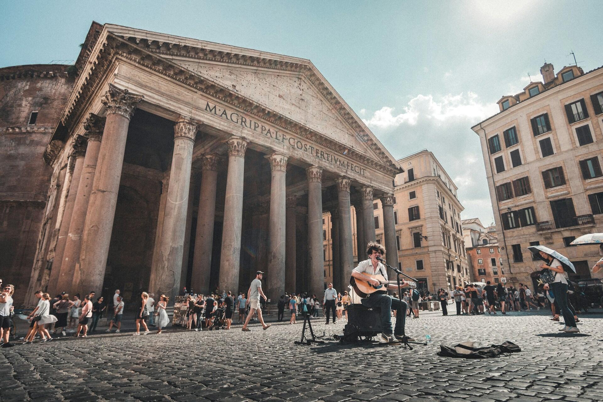 Den enorme kirken Pantheon i Roma på en varm sommerdag, med en gatemusikant i forkant.